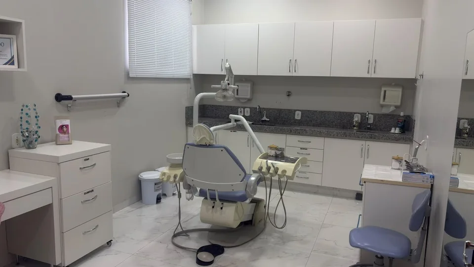 Sala de atendimento do consultório, com cadeira odontológica e armários brancos
