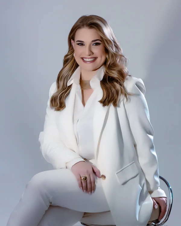 Retrato profissional da Dra. Lara Gimenez sentada, com roupa branca
